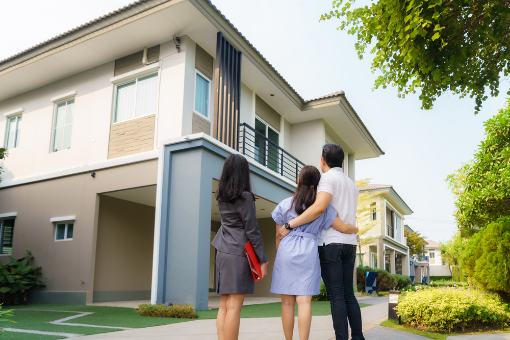 Couple Viewing New Home with Realtor – Property Appraiser San Diego CA A couple stands with a real estate agent while viewing a modern two-story home, symbolizing expert guidance and accurate property evaluation – Property Appraiser San Diego CA