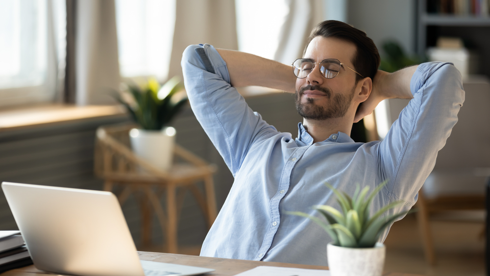 Relaxed Man at Home Office After Successful Home Sale – Sell My House Fast Escondido Confident man leaning back in his chair with hands behind his head, feeling relieved after completing a smooth property sale process – Sell My House Fast Escondido