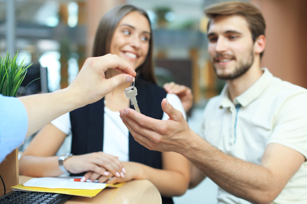 Happy Couple Receiving House Keys – We Buy Houses Richland Smiling couple receiving house keys from a real estate agent after selling their home – We Buy Houses Richland