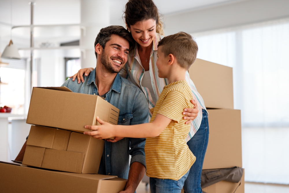 Smiling family packing moving boxes together in their living room, representing a smooth and stress-free home-selling process – We Buy Houses Chula Vista