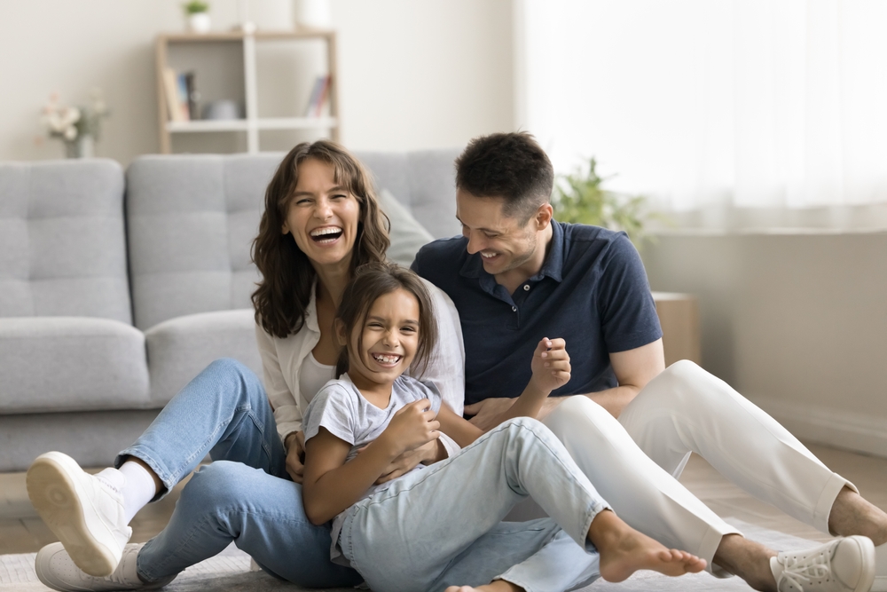 Smiling Family Enjoying New Home – We Buy Houses Vista Happy family laughing together on the living room floor after selling their home quickly and moving into a new house in Vista – We Buy Houses Vista