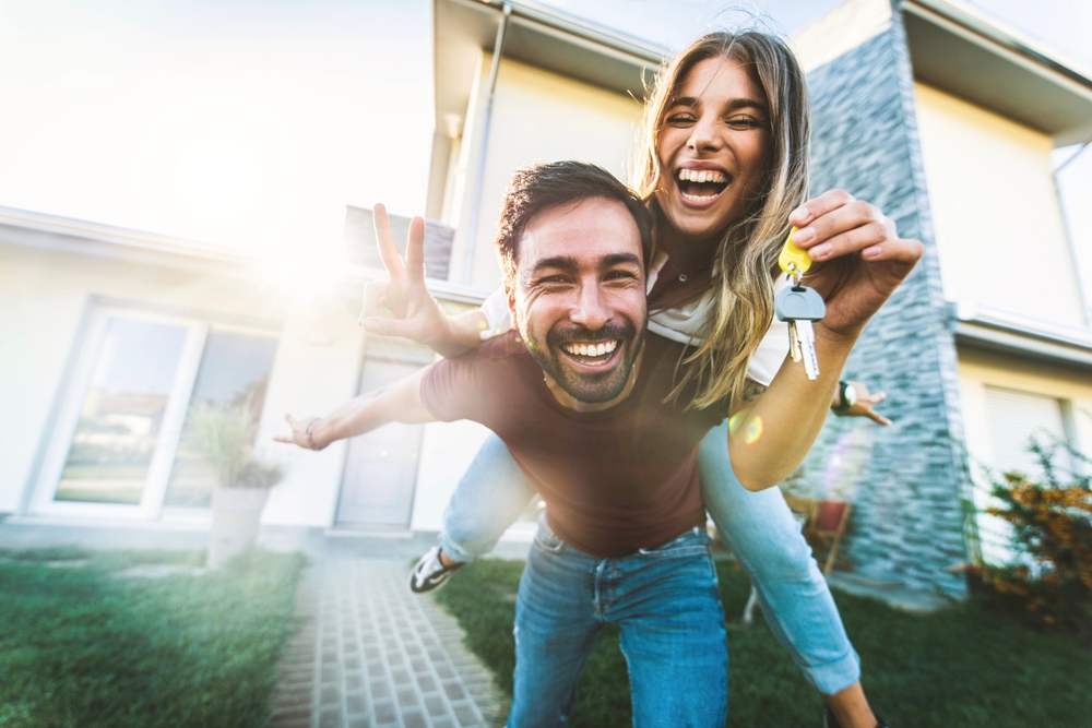 Happy Couple Celebrating New Home Purchase – Sell My House Fast San Diego Joyful couple smiling outside their new home, holding house keys and celebrating a successful property sale in San Diego – Sell My House Fast San Diego