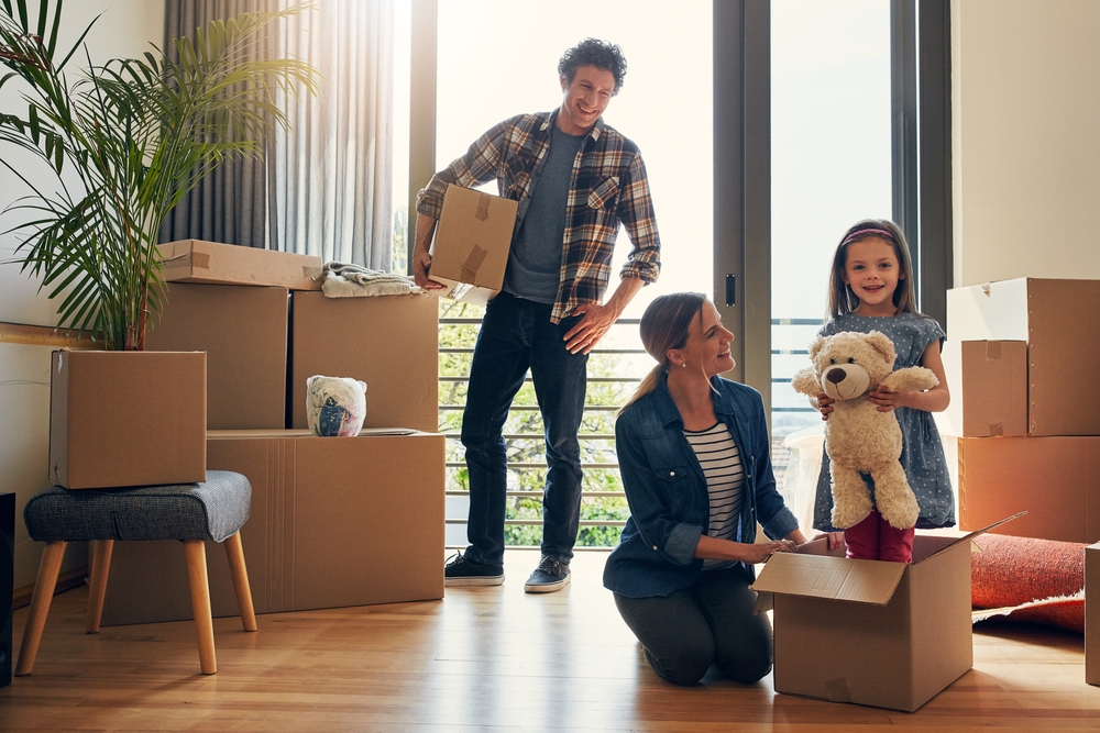Family Packing Boxes During a Move – Sell My House Fast San Marcos Happy family packing moving boxes together in their new home, representing a quick and successful property sale – Sell My House Fast San Marcos