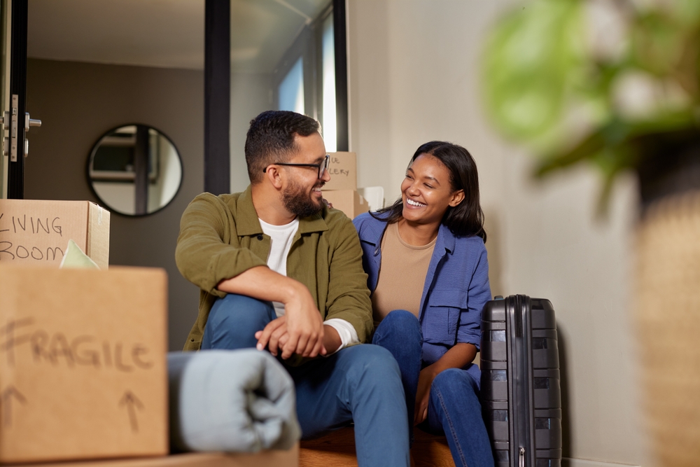Happy Couple Moving After Quick Home Sale – We Buy Houses Vista Smiling couple sitting among moving boxes and luggage after selling their house fast in Vista, California – We Buy Houses Vista